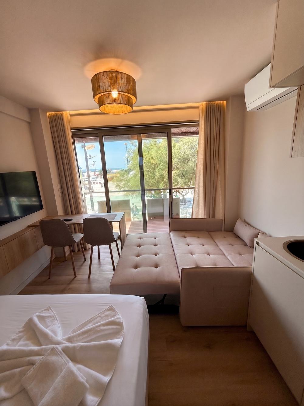 Sofá-cama aberto no estúdio, com mesa de refeições e porta para a varanda