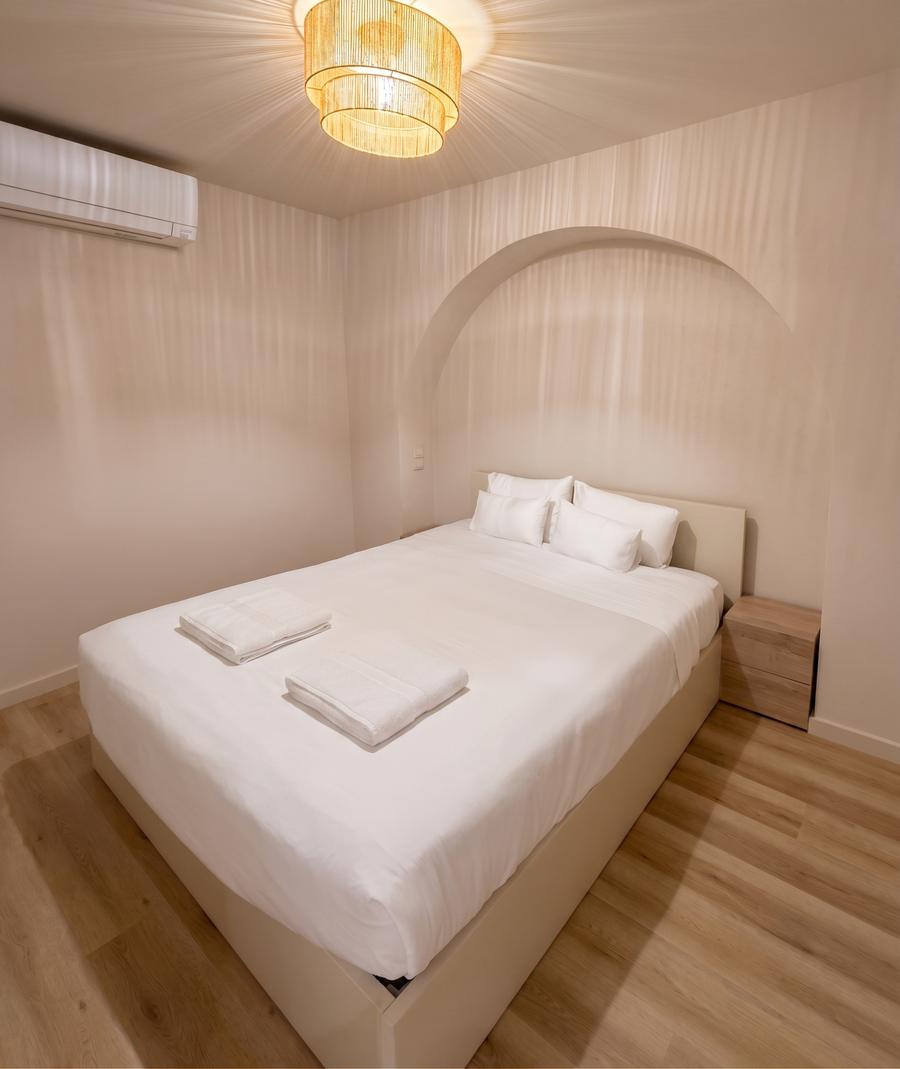 Quarto do T1 com cama de casal e arco decorativo na cabeceira