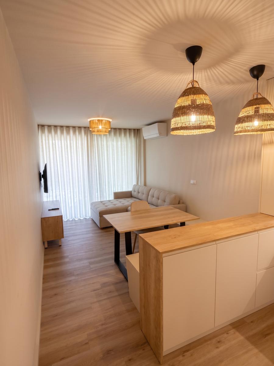 Sala do T1 com sofá-cama, mesa de refeições e SmartTV